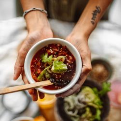 Top view of hands holding a soup bowl with herbs and spices, showcasing culinary art. — Domaine Fourrier review and tasting n