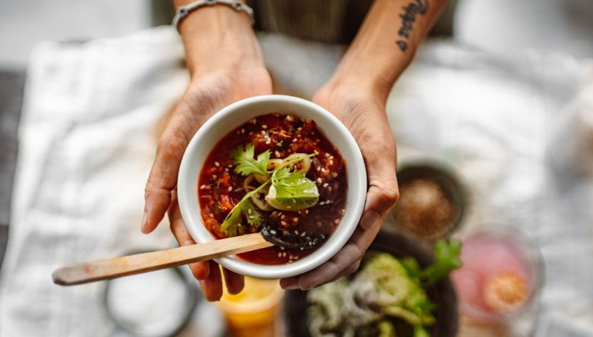 Top view of hands holding a soup bowl with herbs and spices, showcasing culinary art. — Domaine Fourrier review and tasting n