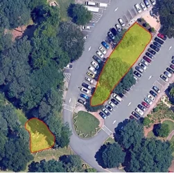 Aerial view of a parking lot outlined with color-coded sections and surrounded by trees.
